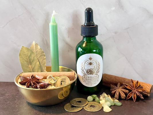 Money bowl with coins, cinnamon, bay leaves, crystals, green candle, and Abundance and Prosperity ritual oil for prosperity magic