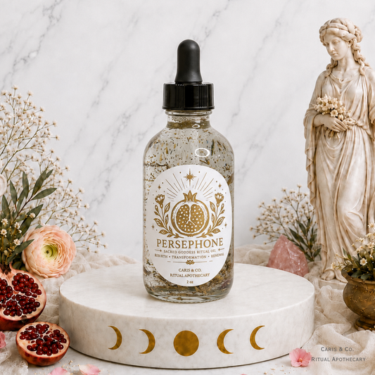 A glass dropper bottle of Persephone Ritual oil by  Caris & Co. Ritual Apothecary sits on a white marble pedestal decorated with gold moon phases.