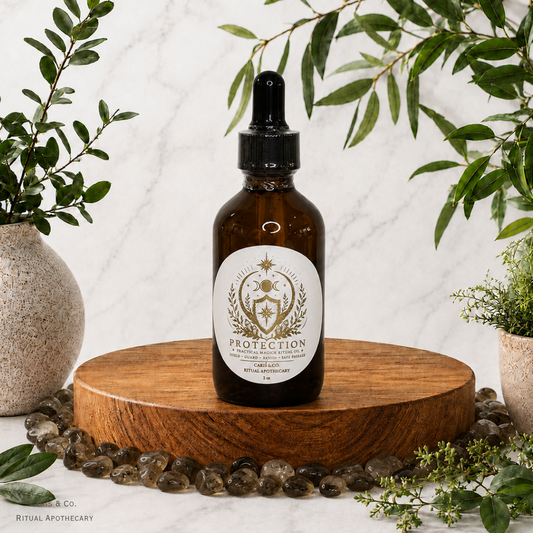 An amber glass dropper bottle labeled 'PROTECTION' by  Caris & Co. Ritual Apothecary, displayed on a round wooden pedestal with green foliage and small stones around it against a light marble background.